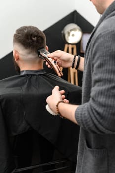 Haircut and alignment of the head contour with a hair clipper and trimmer. Short haircut in the barbershop.