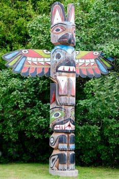 Isolated totem wood pole in the green forest background