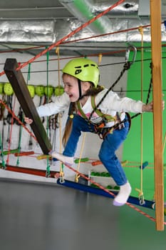 The girl carefully and carefully passes the cableway in the playroom, active recreation for children.