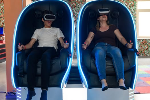 Virtual reality attraction, son and mother experience adrenaline from virtual reality, 5D sensation.