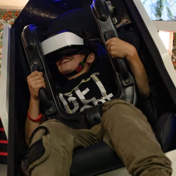 Happy reactions in a child from an attraction with a virtual reaction, virtual reality glasses and children's entertainment.