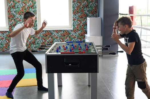 Active recreation in the game room, children play table football, active game for children.