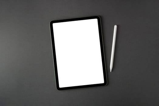 Tablet with blank screen and stylus on dark gray office desk