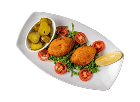 Kibbeh or icli kofte on a white porcelain plate with pickles and salad