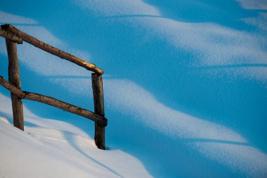 A wooden fence in snow background in winter time