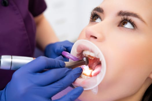 Dentist examines female patient mouth with dental instruments and optragate in private clinic. Professional dental checkup to maintain oral cavity health