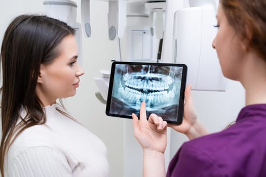 Dentist Presenting Jaw and Teeth Radiograph x ray to Patient in Dental Clinic.