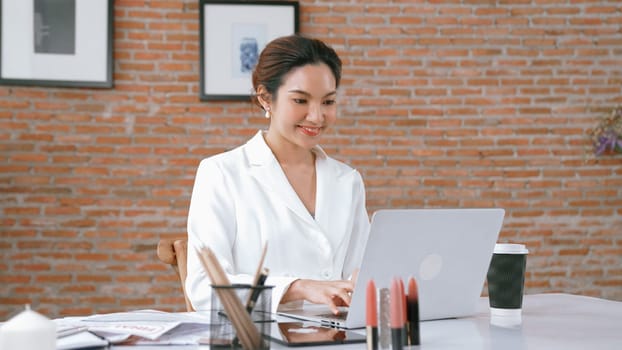 Young businesswoman sitting on the workspace desk using laptop computer for internet online content writing or secretary remote working from home. Vivancy