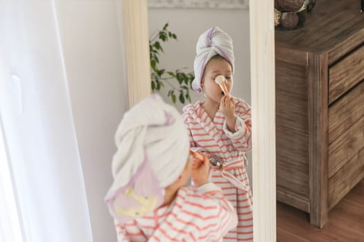 Little girl with a towel on her head doing makeup