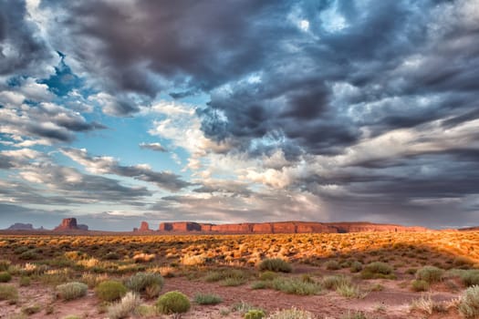 Monument Valley view at sunset with wonderful cloudy sky and lights on mittens