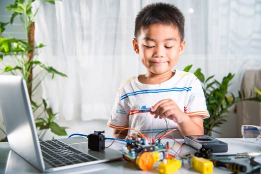 Asian kid boy assembling board into Arduino robot car homework, Little child assemble DC to DC converter into car toy, creating electronic AI technology workshop online school lesson