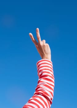 Female hands making peace sign by fingers on sky background. Beautiful hands of woman with copy space. Love concept on Valentine day.