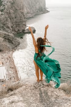 Woman sea green dress. Side view a happy woman with long hair in a long mint dress posing on a beach with calm sea bokeh lights on sunny day. Girl on the nature on blue sky background