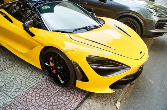 Ho Chi Minh City, Vietnam - 05.07.2023: A yellow car is parked alongside a black car in the automotive parking lot, with their sleek designs and shiny wheels standing out