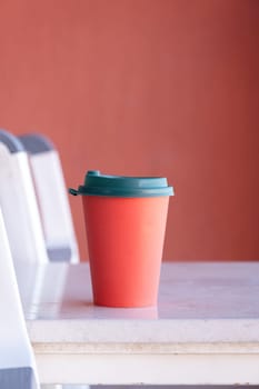 red paper coffee cup on coffee table in the balcony. mockup design, natural light