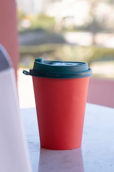 red paper coffee cup on coffee table in the balcony. mockup design, natural light