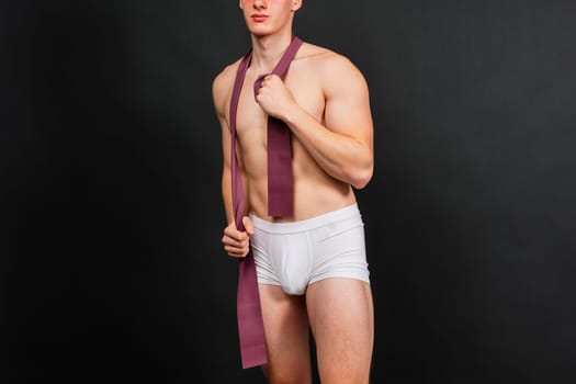 Young bodybuilder working out with rubber band over a white and dark background