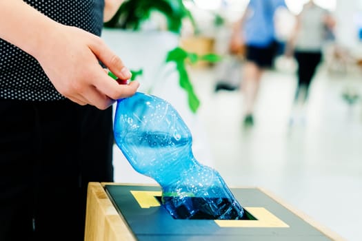 Close up hand throwing an empty plastic water bottle into recycling bin, recycle rubbish