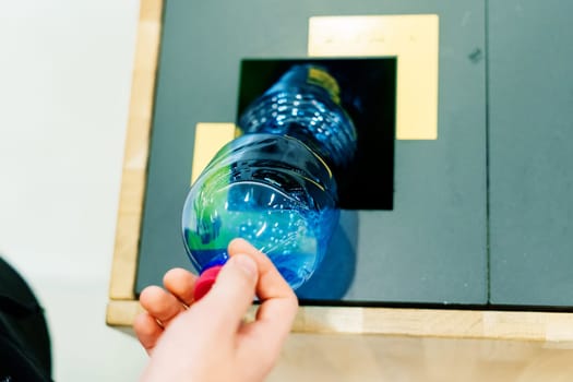 Close up hand throwing an empty plastic water bottle into recycling bin, recycle rubbish