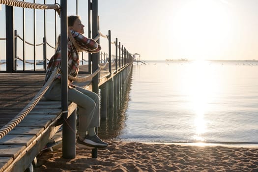 Travel and vacation. Young Woman sitting on a pier in sunrise, enjoying the view