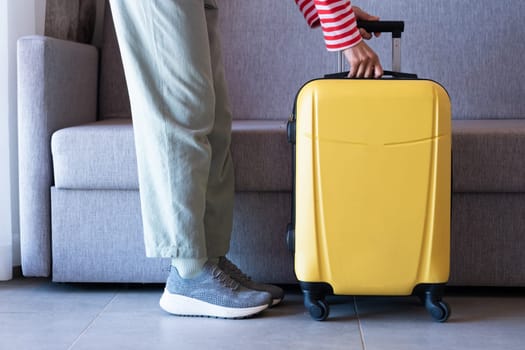 yellow suitcase and woman legs on sofa background in hotel room