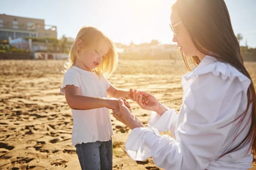 Mom and daughter playing on the beach, holding hands and spending happy moments together. Family relationships. Maternity and babyhood concept