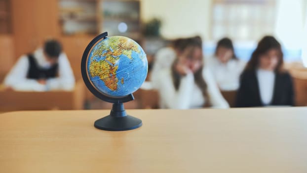 A globe of the world with textbooks in the background of a lesson in a school classroom