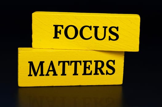 Focus matters text on yellow wooden blocks with dark cover background. Focusing concept.