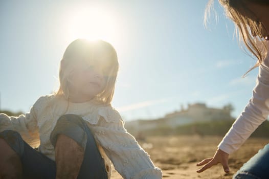 Two adorable little kids girls playing together on the beach, building sandy castle on warm sunny day