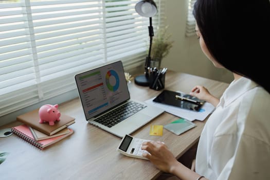 young woman checking bills, taxes, bank account balance and calculating expenses in the living room at home.