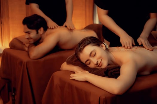 Couple customer having exfoliation treatment in luxury spa salon with warmth candle light ambient. Salt scrub beauty treatment in Health spa body scrub. Quiescent