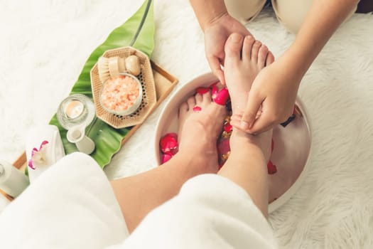 Woman indulges in blissful foot massage at luxurious spa salon while masseur give reflexology therapy in gentle day light ambiance resort or hotel foot spa. Quiescent