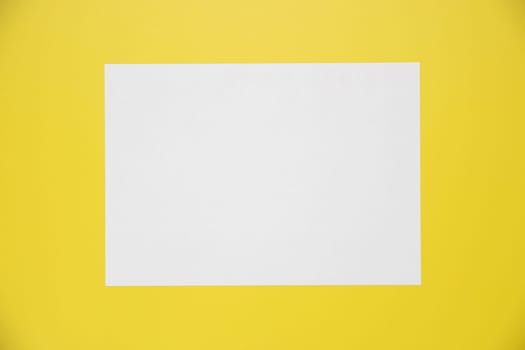 Empty white paper sheet isolated on yellow background.