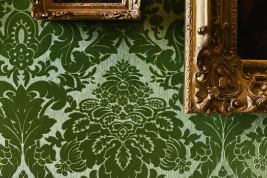 Green velvet wallpaper and gold frames with paintings in castle