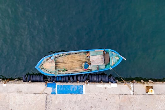 Aerial top view by Drone of the moored small fishing boat at the quay. 