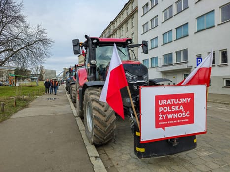 Wroclaw, Poland, February 15, 2024: Farmers protest against the European Union's anti-agricultural policies. Several farm tractors are parked in front of buildings under a cloudy sky