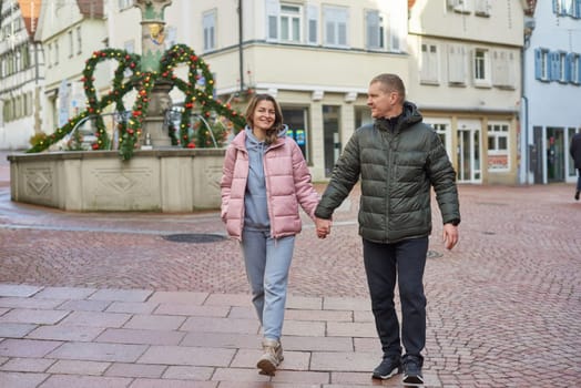 Loving couple of tourists walking around old town. Man woman couple walking europe old town Germany. Couple of lovers leisurely stroll in the cool autumn morning on the streets of a BIETIGHEIM-BISSINGEN (Germany). The guy holds his wife. Vacation, autumn, holiday. Couple Walking in Europe's Old Town