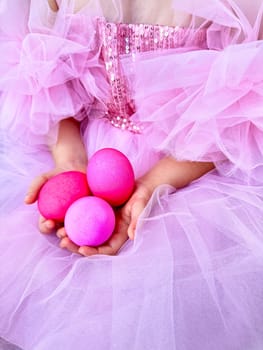 Child in pink tulle dress holding bright pink eggs, Easter celebration concept with a playful and festive feel. For Easter related marketing materials, event invitations, childrens party advertisements. High quality photo