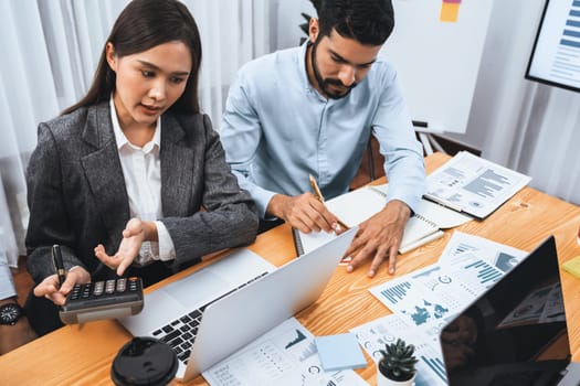 Multiracial analyst team use BI dashboard data to analyze financial report on meeting table. Group of diverse business people utilize data analysis by FIntech for business marketing decision. Concord