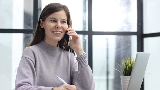 A woman in close-up in the office talking on the phone with her colleagues.