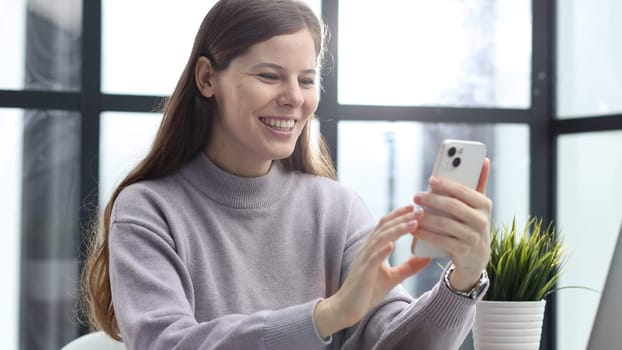 A woman in close-up at a desk in the office talking on the phone and discussing a deal.