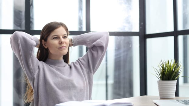 A woman in close-up at a desk in the office resting after work.