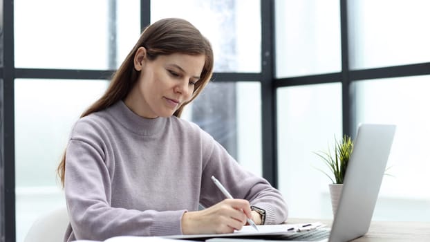 A woman in close-up at a desk in the office conducts a business report.