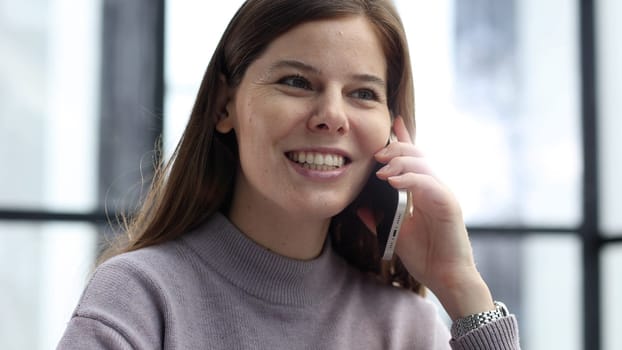 A woman's face is in close-up in the office, she is talking on the phone and discussing a deal.