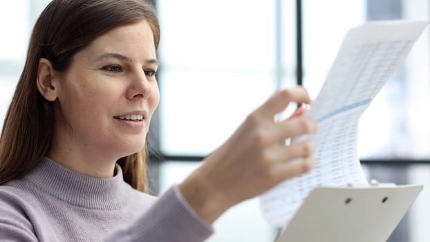 A woman's face is in close-up in the office, she checks the business reports for the past month.