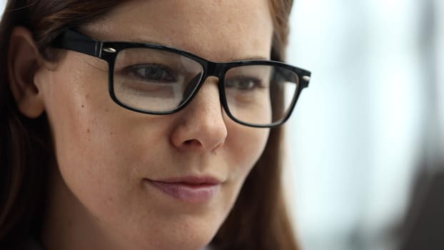 Close-up of a woman's face in the office with glasses.