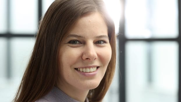 A woman's face in close-up in the office, she looks at the camera.