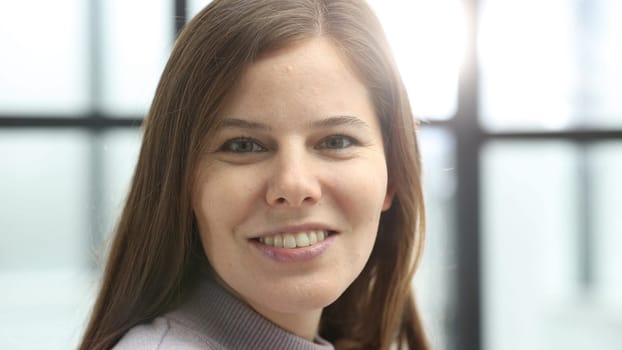 A woman's face in close-up in the office, she looks at the camera.
