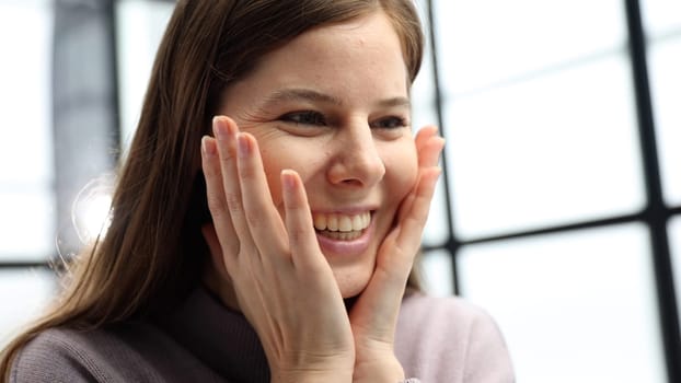 A woman's face is in close-up in the office, she looks at the screen and is surprised.