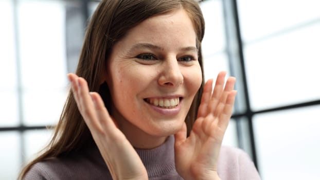 A woman's face is in close-up in the office, she looks at the screen and is surprised.